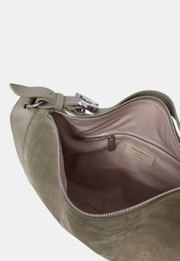 Suede handtas in taupe met zilverkleurige hardware. Beschikt over een ritssluiting en een roze stoffen voering met een binnenvak met ritssluiting. Merktag zichtbaar.