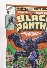 Black Panther-tecknad konst tryckt på ett vitt tyg. Innehåller starka färger: orange, grön och blå. Illustration i seriestil med textelement.