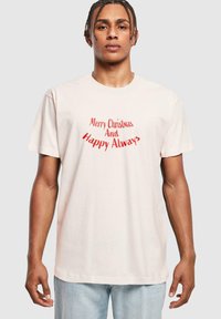 Light pink cotton t-shirt with short sleeves featuring a red graphic text that reads "Merry Christmas And Happy Always," round neckline, relaxed fit.