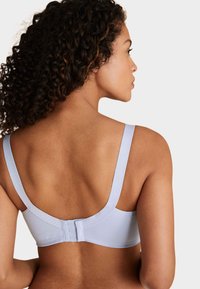 Soutien-gorge bleu clair avec larges bretelles et fermeture à agrafes dans le dos. Présente une texture lisse et un design sans coutures.