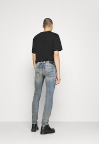 Svart t-shirt med rund hals i kombination med blekta blå smala jeans, som har två bakfickor, samt svarta ankellångstövlar med kraftig sula.