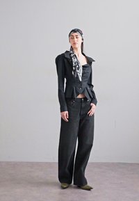 Bluză scurtă neagră cu guler lat, asociată cu pantaloni negri largi și un eșarfă cu model alb-negru. Pantofi verzi cu vârf ascuțit.