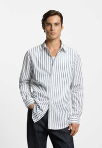 Gestreiftes Hemd zum Zumachen in Weiß mit marineblauen vertikalen Streifen, mit Kragen, langen Ärmeln, Brusttasche und lockerer Passform.