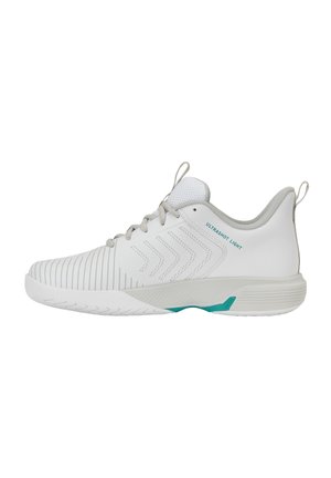 Chaussure de sport blanche basse avec un avant texturé, des lacets gris clair, un liseré gris et des accents turquoise sur la semelle et le texte "ULTRASHOT LIGHT".