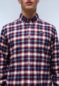 Geruite flanellen overhemd met een blauw, rood en wit ruitpatroon. Button-down kraag met knopen aan de voorkant en een logo patch op de borst.