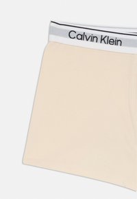 Beżowe bawełniane bokserki o miękkiej fakturze, z czarnym i szarym elastycznym paskiem inskrybowanym "Calvin Klein."