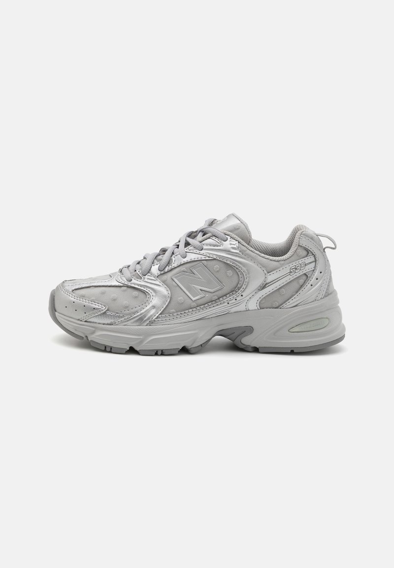 Baskets athlétiques grises avec des panneaux en mesh et en cuir, design à lacets, semelle rembourrée, et logo "N" sur le côté.