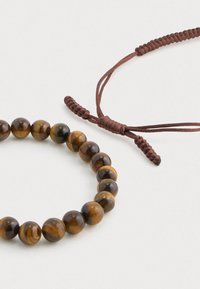 Tigris szemszerű gyöngy karkötő barna és arany árnyalatokban, fonott barna zsinórzárral és sima, polírozott gömbgyöngyökkel.