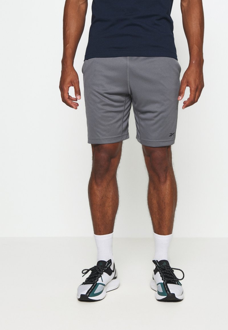 Grå sportshorts i ett mjukt tyg, med resårmidja och sidofickor. Matchas med vita sportstrumpor och löparskor.