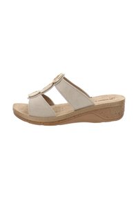 Sandali slide in suede beige con ritagli laterali e due dettagli circolari sulle cinghie. Suola a zeppa con texture in sughero per un supporto aggiuntivo.
