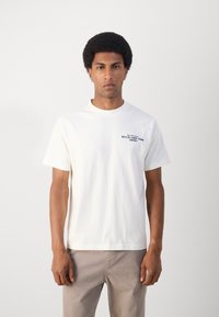 Witte katoenen t-shirt met korte mouwen en een ronde halslijn. Tekst in donkerblauw gedrukt: "BELL' E CAFE' FROM NAPOLI."