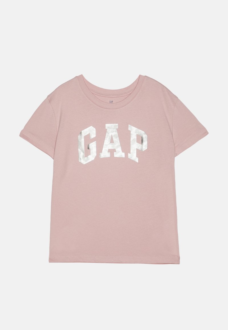 Lys rosa t-skjorte med korte ermer og rund hals, med en tykk, metallisk hvit "GAP" logo på forsiden i blokkbokstaver.