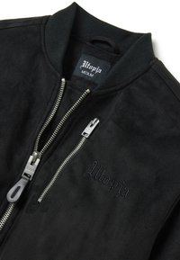 Giubbotto bomber nero realizzato in un morbido materiale simile al camoscio, con colletto a coste, dettagli in zip argentati e logo "Utopia" ricamato.