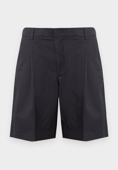Shorts noirs ajustés longueur genou avec passants de ceinture et plis avant sur un fond gris clair uni.