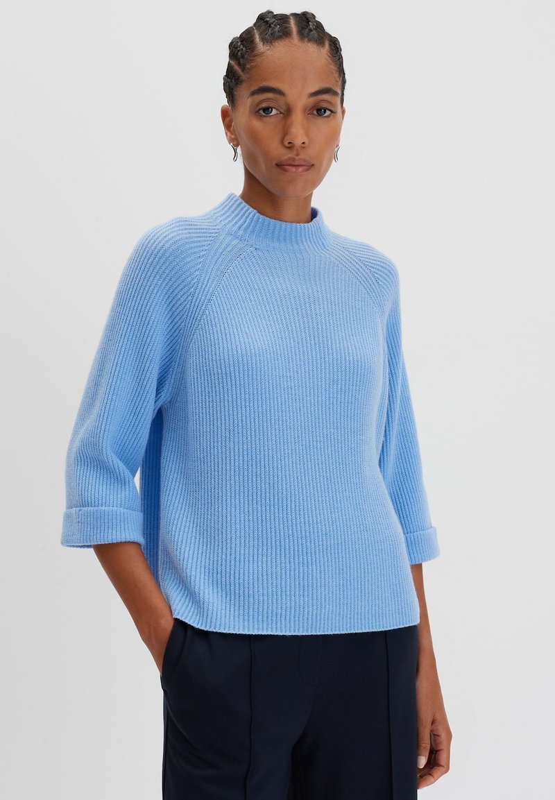 Helles blaues geripptes Sweatshirt mit hohem Kragen, Dreiviertelärmeln und umgeschlagenen Bündchen, gefertigt aus einem strukturierten Strickmaterial.