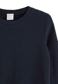 Mörkblå ribbad sweatshirt med rund halsringning och långa ärmar. Tygets textur är något upphöjd med en etikett synlig inuti halsen.