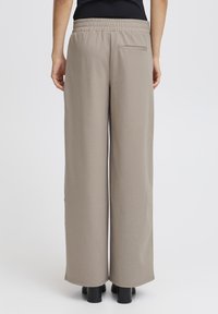 Široke hlače v svetlo bež barvi, narejene iz mehkega materiala. Imajo elastičen pas in eno zadnjo žep. Ravan, subtilen vzorec.