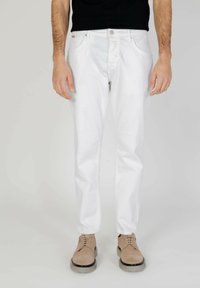 Jeans de algodón blancos con corte recto, que presentan un diseño clásico de cinco bolsillos. Llevados con zapatos beiges de cordones.
