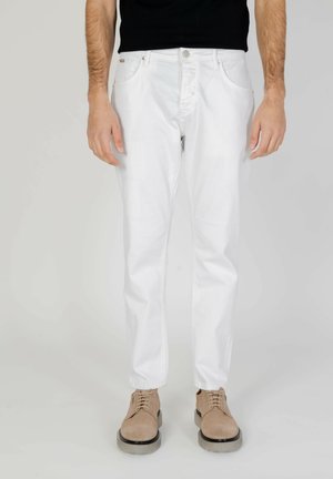 Jeans de algodón blancos con corte recto, que presentan un diseño clásico de cinco bolsillos. Llevados con zapatos beiges de cordones.