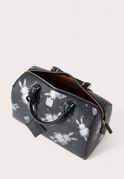 Fekete bőr táska texturált felülettel, lekerekített formával és cipzárral záródik. Fehér nyúl illusztrációk és fekete bőr fogantyúk jellemzik.