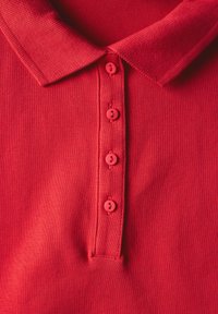 Polo rouge avec un col texturé, patte de boutonnage à cinq boutons de couleur assortie, tissu lisse et subtiles accents côtelés sur les manches.