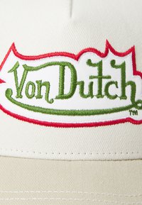 Cream-colored cotton cap featuring a prominent embroidered "Von Dutch" logo in green with red detailing around the edges.