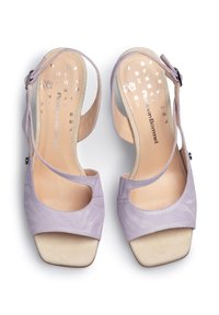 Violetti korkeakorkoiset sandaalit, joissa on teksturoitu pinta, avonainen kärki, nilkkavöitä ja kontrastiväri beigeä mokkaa olevalla alustalla. Sivujen hienovaraiset leikkuut.