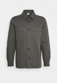 Donkergroen shirt met lange mouwen, knoopsluiting aan de voorkant, twee borstzakken, een puntige kraag en een rechte zoom. Gelaagd stof.