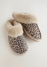 Papučice s uzorkom leoparda, s mekanim bež umjetnim krznom na rubu, ravnim potplatom i detaljima šivanja duž gornjeg dijela. Tekstura je glatka i plišana.