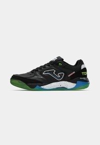 Chaussures de sport noires avec tige en synthétique, accents blancs et bleus, semelle texturée avec un dessous vert et un subtil motif granuleux.