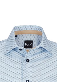 Helles blaues Hemd mit einem kleinen, sich wiederholenden dunkelblauen Muster. Verfügt über einen klassischen Kragen, eine Knopfreihe und marineblaue Knöpfe. Die Innenseite hat tannfarbene Details.