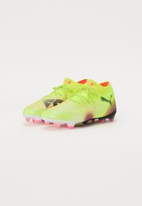 Neon gule fotballsko med teksturert finish, gradientdesign fra rosa til svart, og rosa knotter. Snøring og logodetalj.