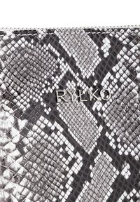 Portafoglio a motivo python in bianco e nero, con superficie testurizzata e logo "RYŁKO" in argento. Chiusura con zip lungo il bordo superiore.