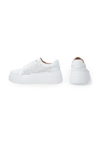 Weiße Sneakers mit dicker Sohle, ausgestattet mit perforierten Seitenpaneelen, runder Zehenpartie und Schnürdesign. Glatte Textur mit minimalistischem Look.