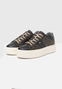 Sneaker in pelle nera e tessuto a motivo con accenti dorati, suola bianca spessa e punta rotonda. Presenta lacci beige e dettaglio del logo.