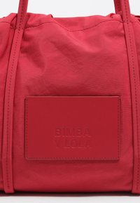 Borsa a mano in nylon rosso con design arricciato, dotata di un'etichetta in pelle rettangolare tessurizzata, impressa con "BIMBA Y LOLA". Esterno liscio con dettagli di cucitura.