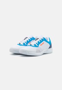 Witte sportschoenen met blauwe accenten en grijze details. Mesh bovenwerk, platte veters en een gebroken rubberen zool voor grip. Kempo-logo zichtbaar.