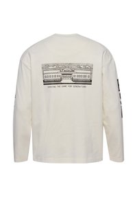 Camisa blanca de manga larga con dibujo lineal negro de un estadio y texto "STADIUM" y "SERVING THE GAME FOR GENERATIONS" en la parte trasera.