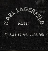 Tissu noir orné de strass brillants. Le texte indique "KARL LAGERFELD PARIS 21 RUE ST-GUILLAUME" dans une police de caractères en gras.