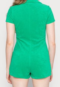 Zielony krótki kombinezon z kołnierzykiem, wykonany z miękkiej tkaniny, o dopasowanym kroju i gładkiej fakturze.