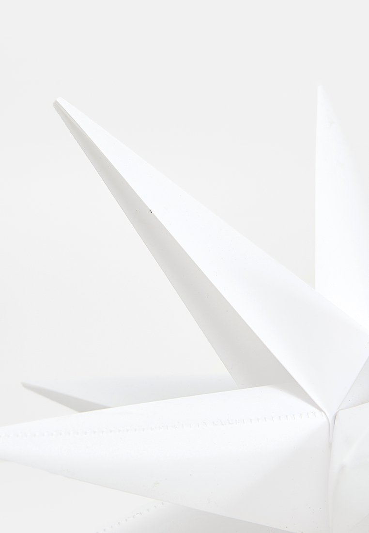Weißer geometrischer Stern mit scharfen, langen Spitzen und einer glatten, matten Oberfläche, vor einem schlichten Hintergrund platziert.