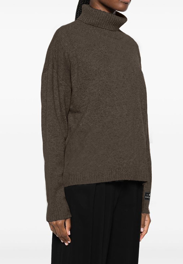 Brązowy sweter z golfem o teksturowanym wzorze, luźnym kroju i długich rękawach. Posiada małą metkę z logo na dolnym brzegu.