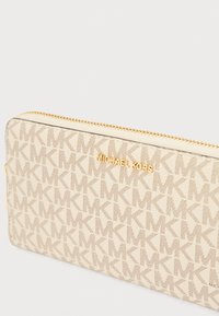 Πορτοφόλι Michael Kors σε μπεζ χρώμα με ανάγλυφο μοτίβο με το λογότυπο και χρυσά μεταλλικά στοιχεία. Διαθέτει φερμουάρ κλεισίματος και ορθογώνιο σχήμα.