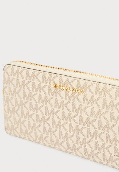 Portefeuille Michael Kors beige avec un motif de logo texturé et des ferrures dorées. Il présente une fermeture éclair et une forme rectangulaire.