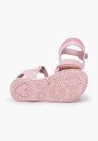 Sandalias rosas con una parte superior de cuero suave, tiras ajustables y suelas de goma con patrones que presentan diseños de estallido solar y corazones.