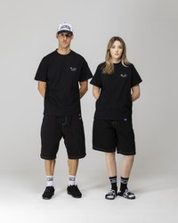 Black cotton t-shirts with a small colorful logo, paired with black shorts. Model wears black shoes and mismatched socks with a logo.