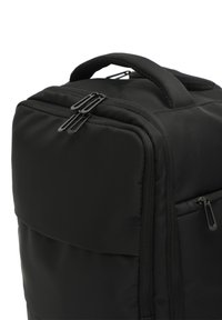 Black soft fabric backpack with padded handle and multiple zippered compartments shown close-up on white background.