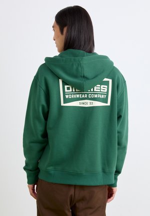 Green hooded sweatshirt with a relaxed fit. Features a large cream-colored logo on the back, ribbed cuffs, and hem. Smooth texture.