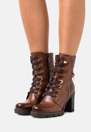 Braune Lederknöchelstiefel mit Schnürung vorne, Metallösen, seitlichem Reißverschluss, strukturiertem Rücken und chunky hohem Absatz.
