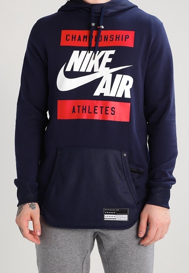 Marinblå Nike Air hoodie med en framficka, vit logotyp, röd text och accentdetaljer. Har en dragkedja i huvan och en texturerad yta.
